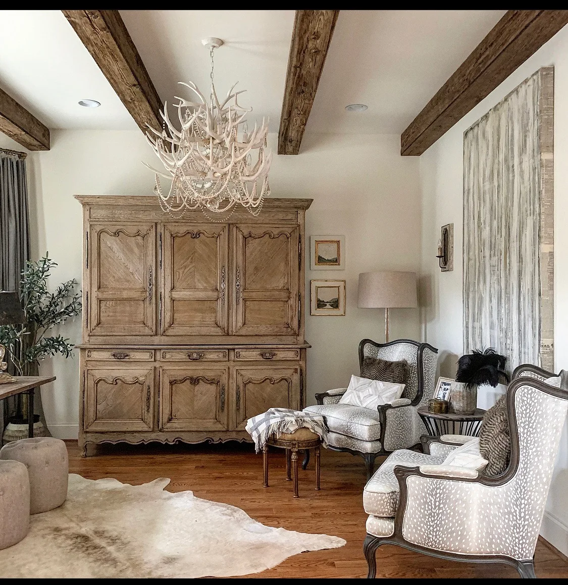 Rustic living room featuring weathered exposed ceiling beams, reclaimed wood wall paneling, and warm hardwood flooring in a farmhouse-style interior.