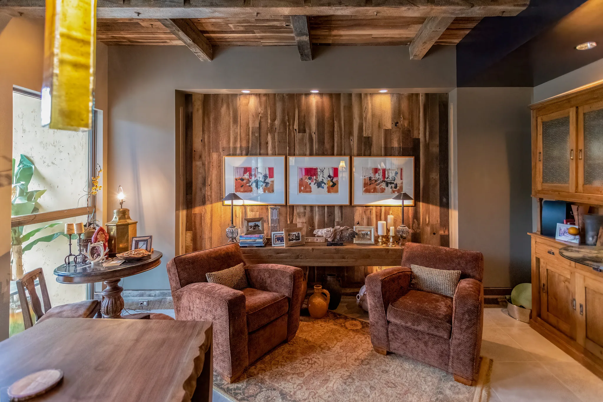 Reclaimed barnwood wall paneling and exposed ceiling beams create a warm, rustic focal point in this living room with vintage character.
