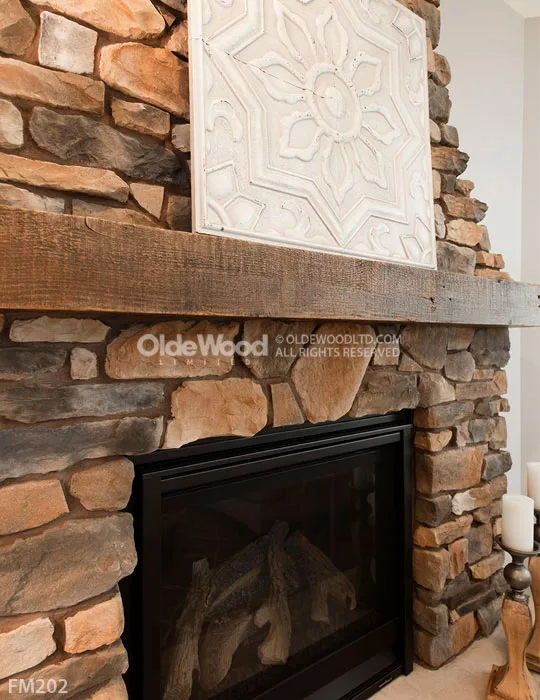 Rustic reclaimed wood fireplace mantel mounted on stacked stone surround with decorative white tin ceiling tile accent above black gas insert.
