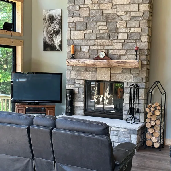 Live-edge wood slab fireplace mantel mounted on stacked stone surround creates a rustic focal point in this modern living room.