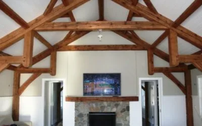 Dramatic exposed timber frame ceiling beams and reclaimed wood fireplace mantel create a striking focal point in this contemporary living room with stone surround.