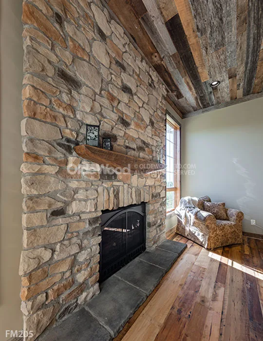 Reclaimed barnwood ceiling beams and fireplace mantel complement mixed-width hardwood flooring in a rustic living room with stone fireplace surround.